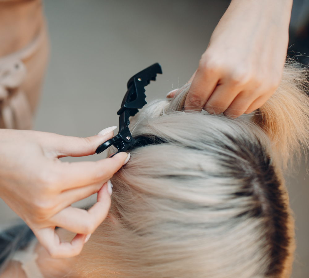 Frisör som sätter upp blont hår inför styling